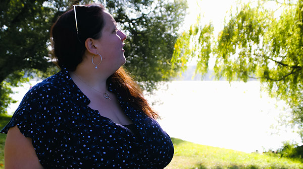 Portrait de Pauline, magnétiseuse, dans un cadre naturel lumineux. Elle est tournée vers la lumière, entourée de verdure et de sérénité, reflétant une connexion harmonieuse avec la nature et une énergie apaisante.